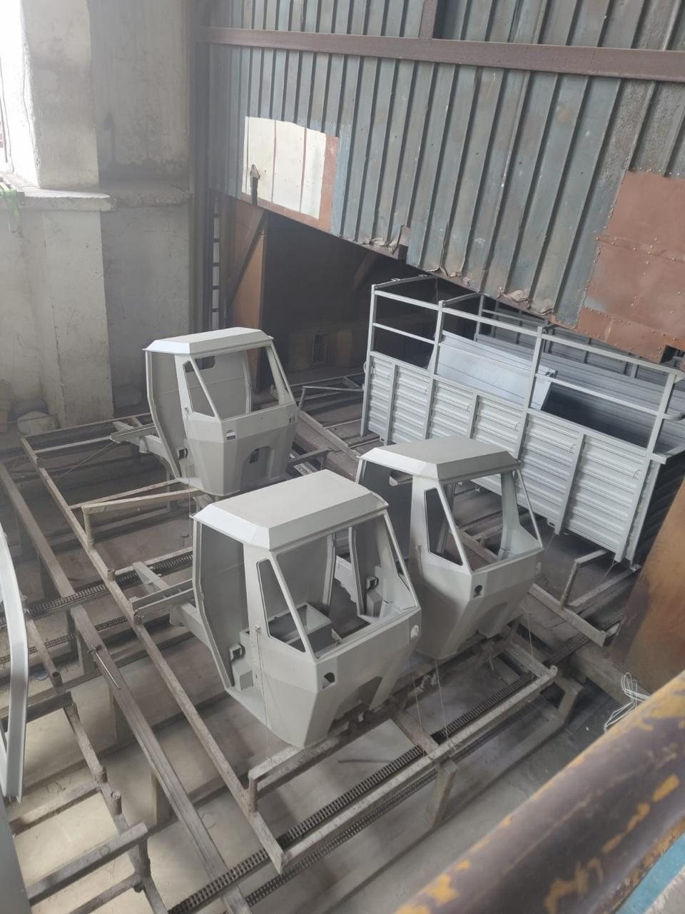 A batch of grey ED-coated cabs and cargo boxes racked before paint