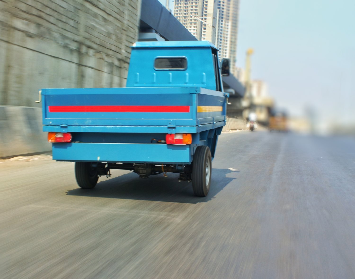 Rear three-quarter view of the blue pilot pickup on the road